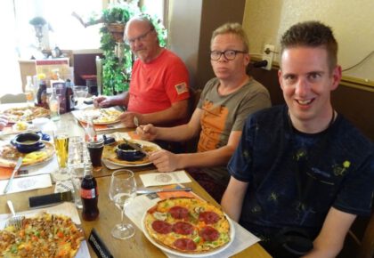 Drie mannen eten pizza in restaurant